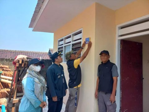 Ketua LPM Kelurahan Kukusan Syafrudin Abto menempelkan plakat pada RTLH, disaksikan Lurah Kukusan Abdul Manan, di wilayah Kukusan. (dok.Kukusan)