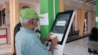 Warga sedang melakukan pendaftaran dimesin anjungan mandiri di Puskesmas Beji.