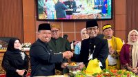 Ketua DPRD Kota Depok, Ade Supriatna ( kanan), menyerahkan potongan tumpeng kepada Wali Kota Depok Supian Suri (kiri). (dok. Icha).