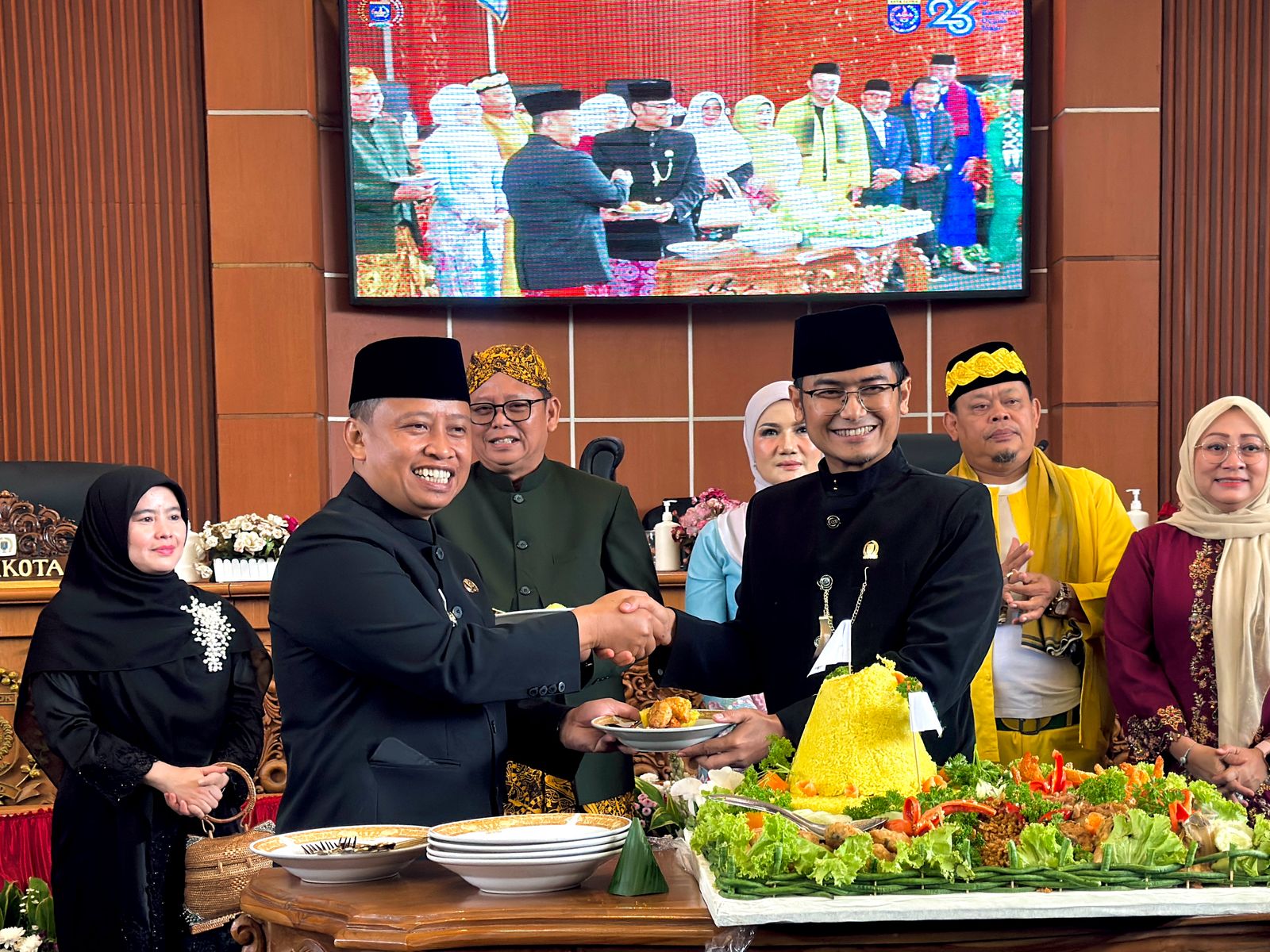 Ketua DPRD Kota Depok, Ade Supriatna ( kanan), menyerahkan potongan tumpeng kepada Wali Kota Depok Supian Suri (kiri). (dok. Icha).